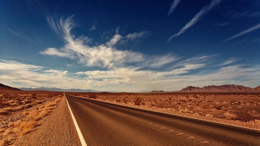 Carretera en el desierto que lleva hacia unas montañas al fondo